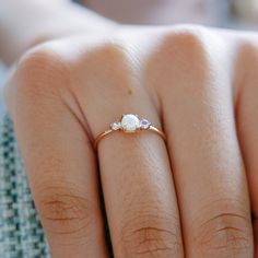 a woman's hand with a gold ring and three stones on the middle finger