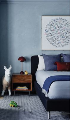 a bed room with a neatly made bed next to a night stand and a painting on the wall