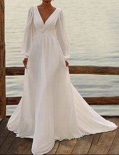 a woman in a white dress standing on a dock