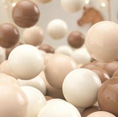 an assortment of chocolate and white balloons floating in the air with string lights behind them