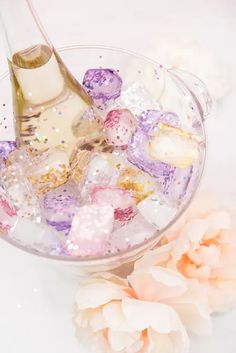 a glass bowl filled with ice cubes next to a pink flower on top of a table