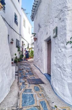 an alley way with white buildings and cobblestone pavement