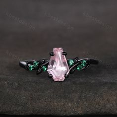 a pink and green ring with leaves on the side, sitting on a stone surface