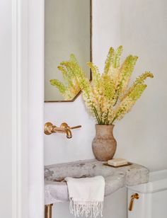 a bathroom with a sink, mirror and flowers in a vase on the counter top