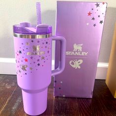 a purple travel mug with stars on it next to a box