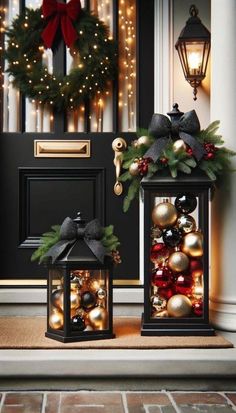 two lanterns with christmas decorations on them sitting in front of a door decorated for the holiday season