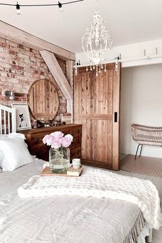 a bedroom with brick walls and white bedding has a chandelier hanging from the ceiling