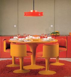 an orange table and chairs in a room with red rugs on the floor next to it