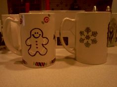 two coffee mugs sitting on top of a counter next to each other with designs on them