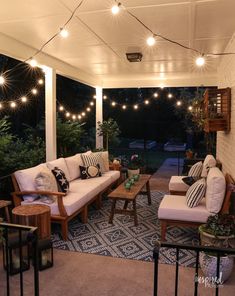 a covered patio with white furniture and string lights