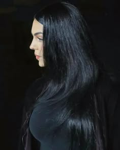 a woman with long black hair standing in the dark