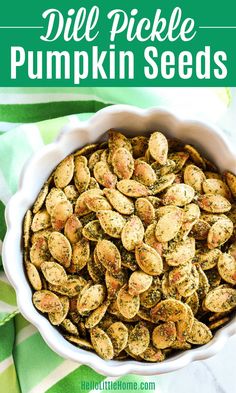 a white bowl filled with pumpkin seeds on top of a green and white table cloth