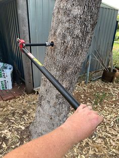 a man is holding a large metal pole near a tree