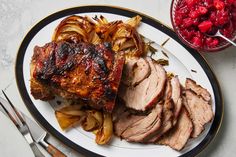 a white plate topped with meat and vegetables next to a bowl of cranberry sauce