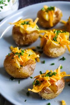 baked potatoes topped with cheese and chives on a white plate