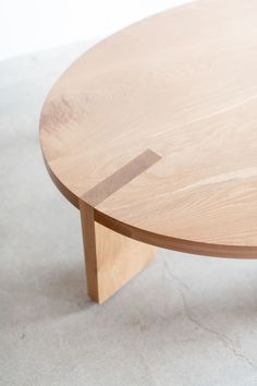 a round wooden table sitting on top of a white carpeted floor next to a wall