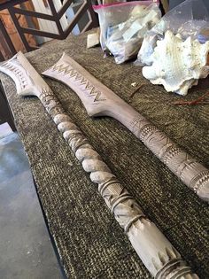 two carved wooden knives sitting on top of a table next to shells and other items