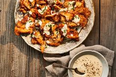 a white plate topped with chicken wings next to a bowl of ranch dressing