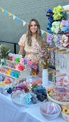 a woman standing in front of a table filled with items