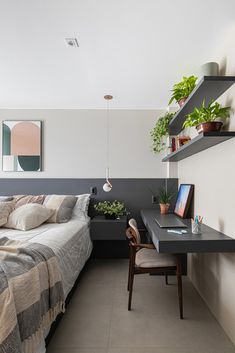 a bed sitting next to a desk with a laptop on top of it in a bedroom