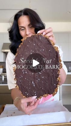 a woman holding up a large piece of cake in front of her face with the words speed, nut, chocolate bark on it