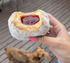 a person holding a doughnut with jelly in it and a dog on the other side