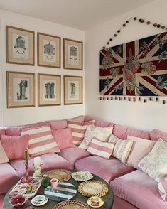 a living room filled with pink couches and plates on top of a coffee table