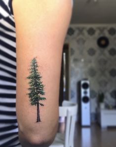 a small pine tree tattoo on the arm