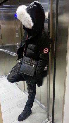 a person standing in an elevator with a handbag on their shoulder and wearing a black jacket