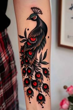 a woman's leg with a black and red peacock tattoo on the side of her arm