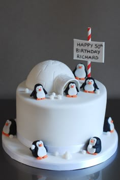 a birthday cake decorated with penguins and an igloo