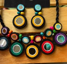 a necklace and earring set made out of fabric with colorful beads on display in a store