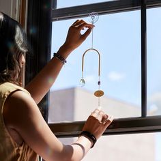 a woman is holding a wind chime in front of a window