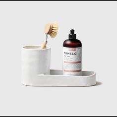 a white cup with a wooden brush in it next to a soap dispenser