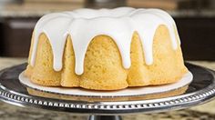 a bundt cake with white icing sitting on top of a metal tray next to a counter