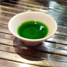 a white bowl filled with green liquid on top of a wooden table