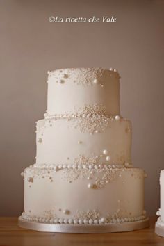 a three tiered wedding cake with pearls on it