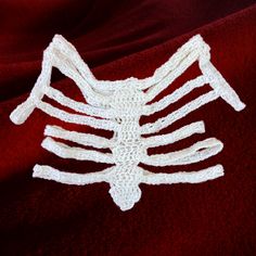 a crocheted skeleton is laying on a red blanket