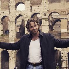 a man standing in front of an old building with his arms out and hands outstretched