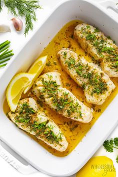 chicken with lemon and herbs in a white casserole dish