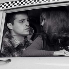 a man and woman sitting in the back seat of a car looking at each other