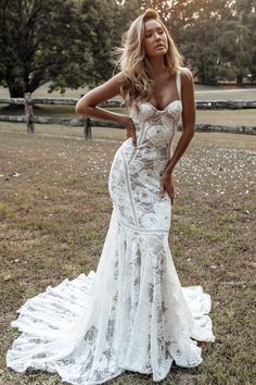 a woman in a white wedding dress posing for the camera with her hands on her hips