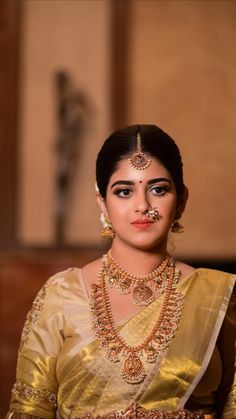 a woman in a yellow sari with jewelry on her neck and chest, looking at the camera