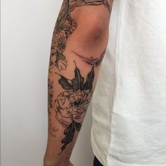 a man with a tattoo on his arm holding a fish and flowers in front of him