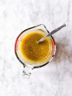 a blender filled with yellow liquid on top of a white counter next to a spoon