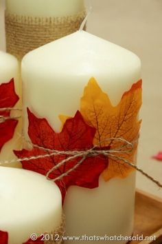 three candles with autumn leaves on them are sitting on a tray next to twine twine