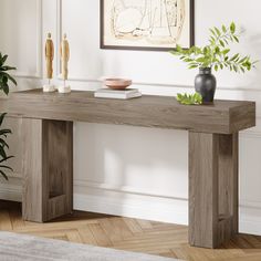 a wooden table with two vases on top of it next to a plant in a room