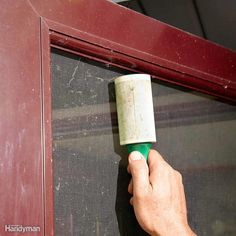 a person holding a roll of toilet paper in front of a red door with a green handle