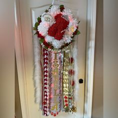 a door hanger decorated with ribbons and flowers in the shape of a heart is hanging on a door