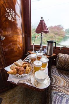 a table filled with food and drinks on top of a wooden table next to a window